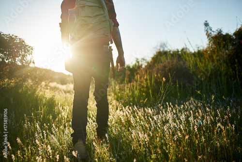 male millennial hiker walking through grass in southern california during sunset