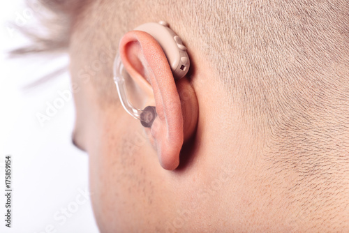 Young man hearing impaired dressing the hearing aid. At isolated white background.