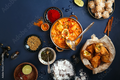 Indian cuisine on diwali holiday: tikka masala, samosa, patties and sweets with mint chutney and spices. Dark blue background. Diwali celebration dinner