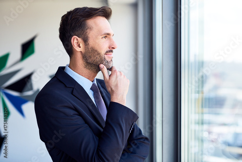 Thoughtful businessman looking through window in office