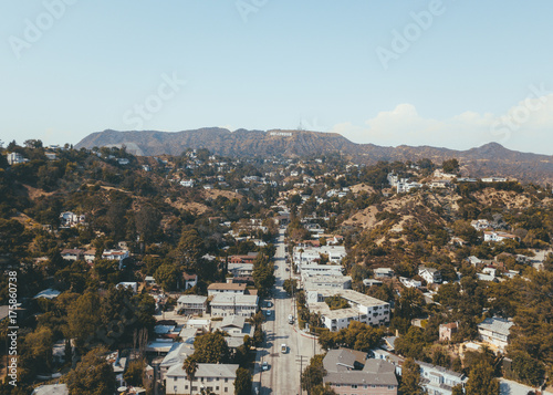 Hollywood sign district in Los Angeles, USA. Beautiful Hollywood highway road with cars, palms and a sign on the hills. Clear blue sky.