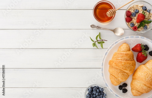 Continental breakfast with croissants and berries on white wood