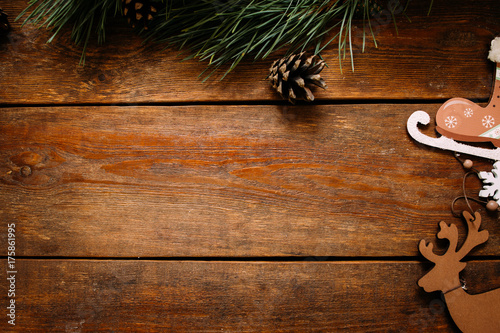 Christmas and New Year holiday background. Close up handmade ornaments of skate and deer on right and pine with strobila above on wooden table, festive decoration concept. Free space in the middle photo