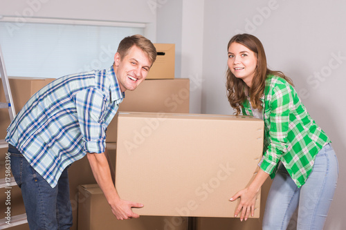 Happy young couple unpacking or packing boxes and moving into a new home. © satura_