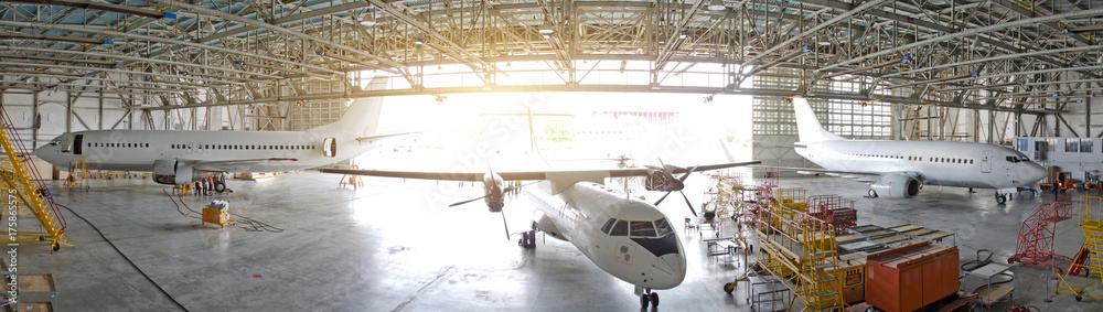 Three passenger aircraft in a hangar with an open gate for service, view of the panorama. - obrazy, fototapety, plakaty 