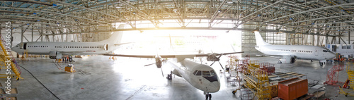 Three passenger aircraft in a hangar with an open gate for service, view of the panorama.