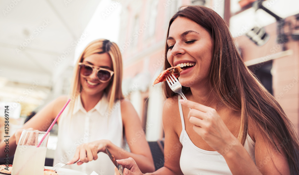 Pizza time. Young girls eating pizza in a cafe. Consumerism, lifestyle Pizza time. Young girls eating pizza in a cafe. Consumerism, lifestyle