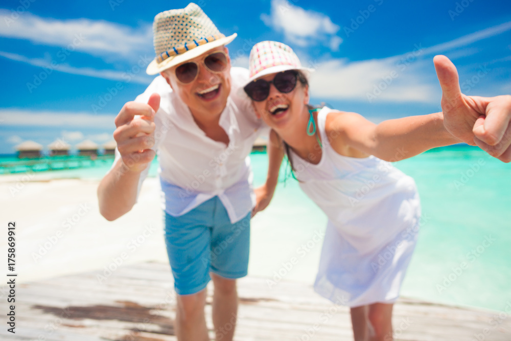 happy young couple in white clothes having fun by the beach