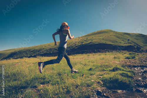 fitness woman trail runner running on grassland trail