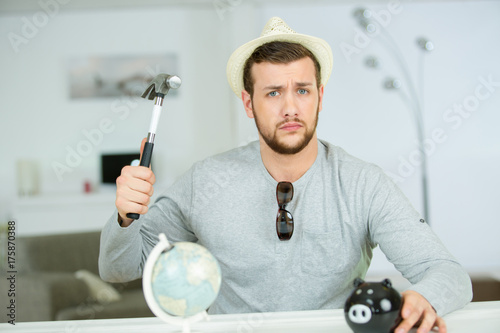 serious man breaking piggy bank with hammer photo