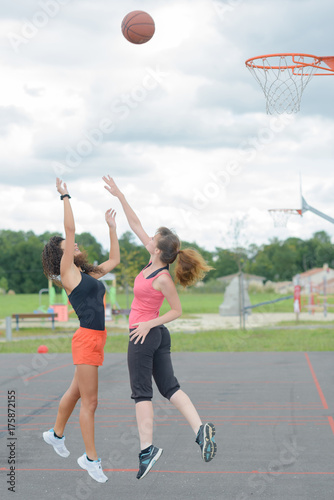 Ladies mid air reaching for basket ball