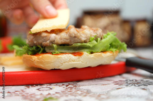 Cooking of burgers with veal, red tomatoes, lettuce, cheese and sauce in the home kitchen