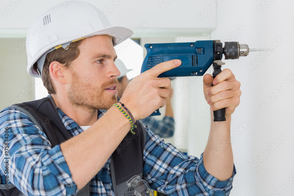 young handsome handyman using a drill at work young handsome handyman using a drill at work