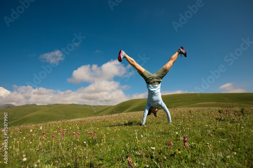 woman doing a handstand in a mountain peak meadow photo