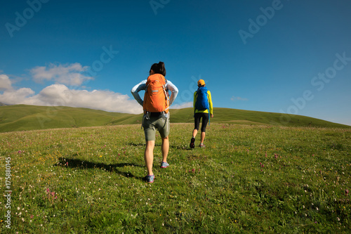 two backpacking women friends hiking in grassland mountains