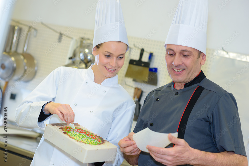 pastry chef and assistant preparing cake