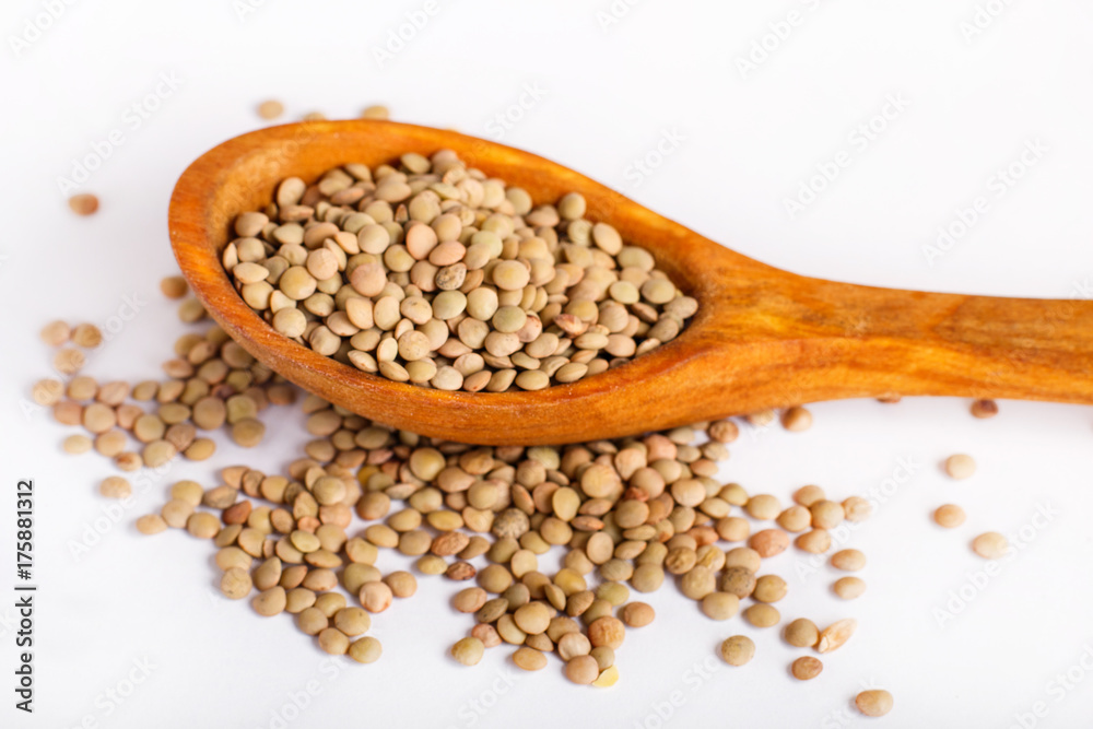 Pile of green lentils in a wooden spoon isolated on white background. Pile of green lentils in a wooden spoon isolated on white background.
