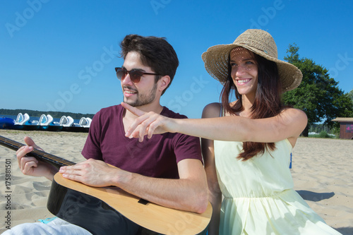 young man with his guitar and girlfriend on the beach © auremar