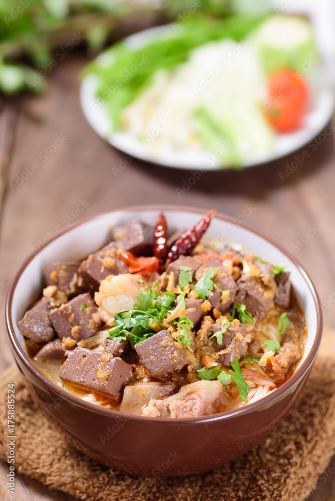 Northern Thai food (Kanom Jeen Nam Ngeaw) with vegetables on wooden background,spicy rice noodles soup,rice vermicelli served with curry Northern Thai food (Kanom Jeen Nam Ngeaw) with vegetables on wooden background,spicy rice noodles soup,rice vermicelli served with curry