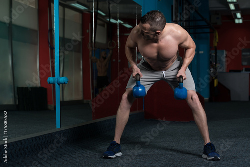 Fitness Man Using Kettlebells Inside Gym