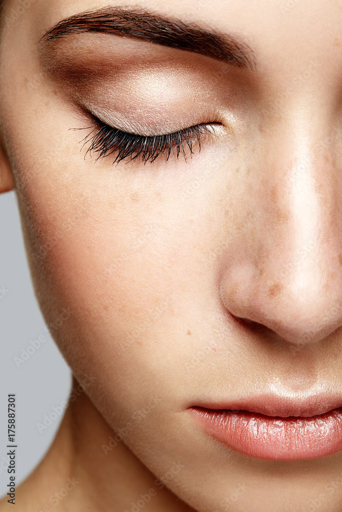 Fototapeta premium Closeup macro portrait of female face with closed eyes. Human woman half-face with day beauty makeup. Girl with perfect skin and freckles
