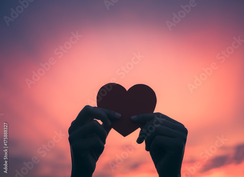 Closeup hand holding red heart during sunset background. Happy, Love, Valentine's day idea, sign, symbol, concept.