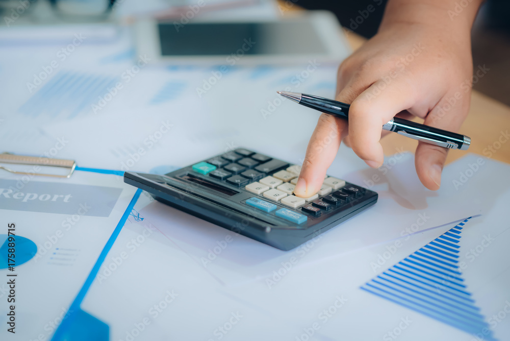 Business analysis - calculator, sheet, graphs (business report) and analyst hand Business analysis - calculator, sheet, graphs (business report) and analyst hand