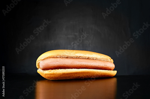 Plain hotdog with big sausage isolated on black background. Front view.