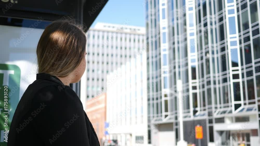 A Corporate businesswoman commuter waits for a bus in downtown city A Corporate businesswoman commuter waits for a bus in downtown city