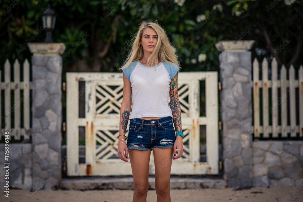 Summer portrait of a young stunning blonde girl. Wears a white tshirt and denim shorts. Outdoors, lifestyle, fashion Summer portrait of a young stunning blonde girl. Wears a white tshirt and denim shorts. Outdoors, lifestyle, fashion