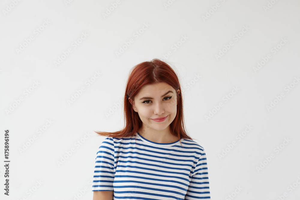 Horizontal studio picture of charming gorgeous young Caucasian female wearing sailor shirt smiling and raising one eyebrow, looking at camera with mysterious cunning expression on her pretty face Horizontal studio picture of charming gorgeous young Caucasian female wearing sailor shirt smiling and raising one eyebrow, looking at camera with mysterious cunning expression on her pretty face