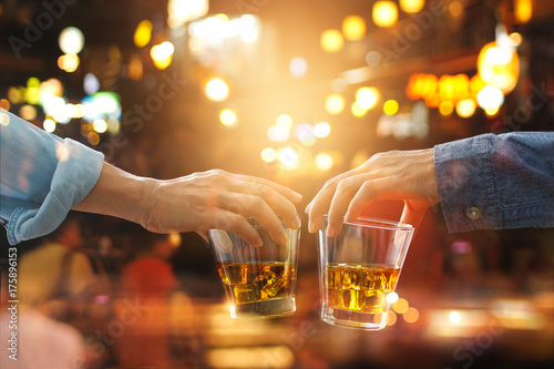 Valokuva Cheers clinking of friends with bourbon whiskey drinks in party night after work