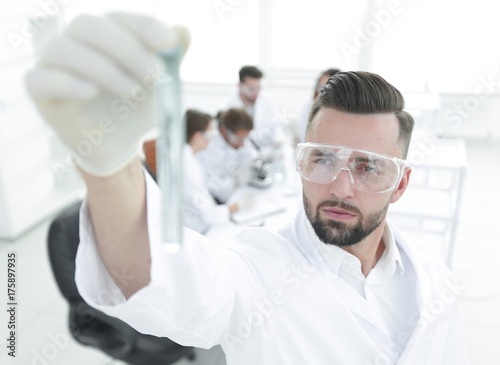 image is blurred. young scientist holding tube with the reagents