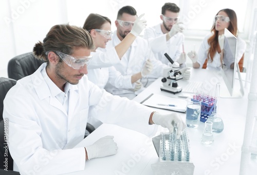 Scientists working with a microscope and make notes in the workplace