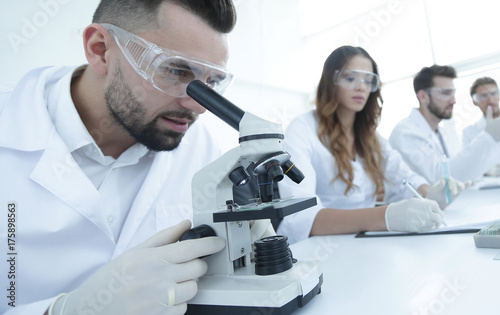 male laboratory technician looking at samples in the microscope