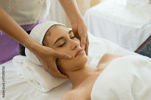 Young beautiful woman having face massage relaxing in spa.