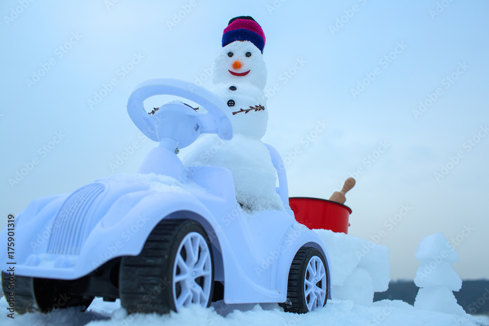 Obraz premium Snowman driving toy car on white sky