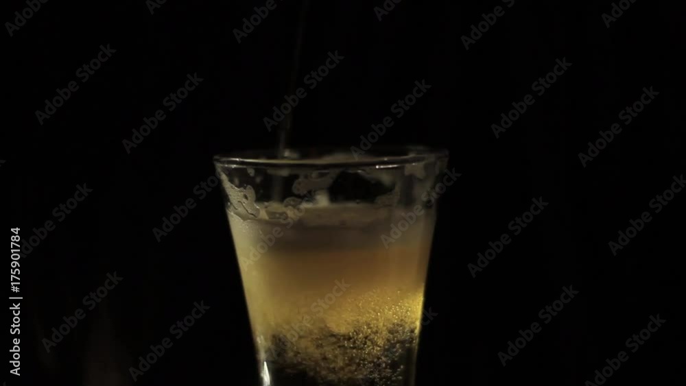 Pouring beer into a glass on a black background Pouring beer into a glass on a black background