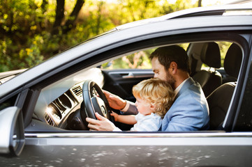 Man driving a car with little son.