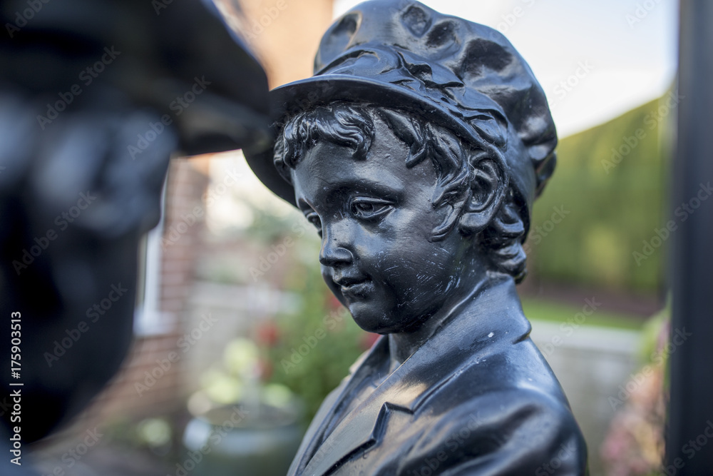 Black metal or bronze garden statue of a Victorian girl wearing a hat