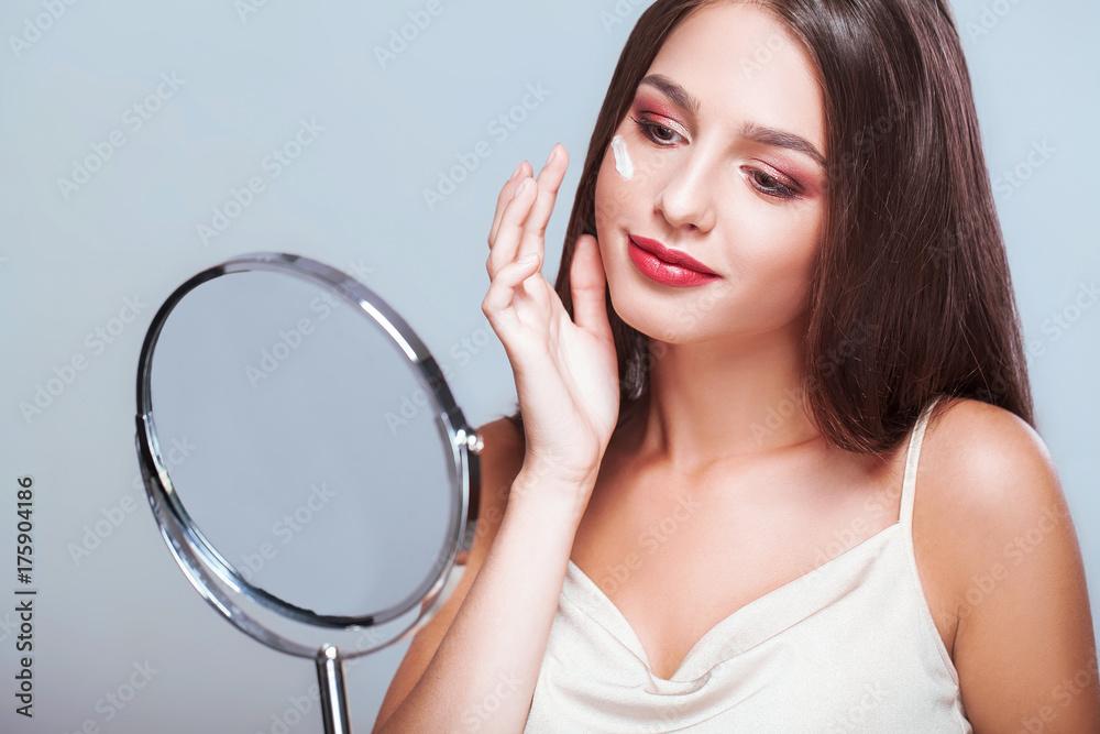 Happy woman with healthy face applying cream under the eyes Happy woman with healthy face applying cream under the eyes
