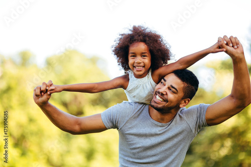 Portrait of young father carrying his daughter on his back photo