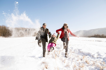 Father and mother with their daughter, playing in the snow.