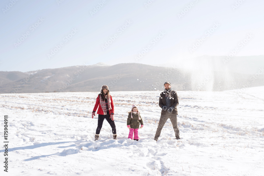 Father and mother with their daughter, playing in the snow.