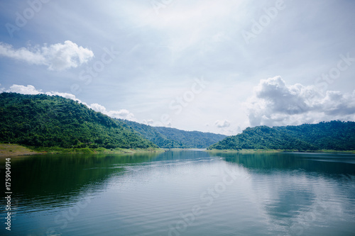 Fototapeta Naklejka Na Ścianę i Meble -  Lake with Mountains.Relax summer wallpaper, daytime landscape with lake among the wooded green mountains, beautiful blue cloudy sky. Khun Dan Prakan Chon Dam, Thailand.