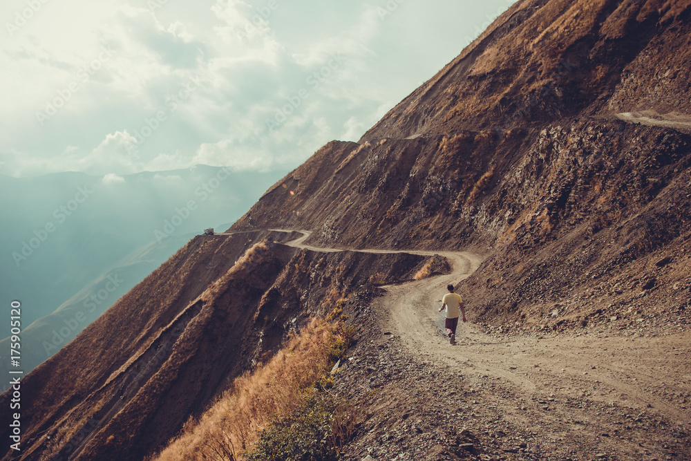 Fototapeta premium Spectacular and dangerous mountain road, Tusheti, Georgia. Adventure concept. Mount landscape. Unpaved winding road. Dirt serpentine road. Sunlight rays. Explore the world. Travel to Caucasus. Autumn