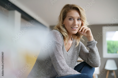 Attractive middle-aged blond woman relaxing in armchair