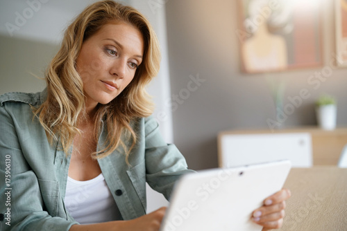 Woman sitting at home websufing on internet with digital tablet