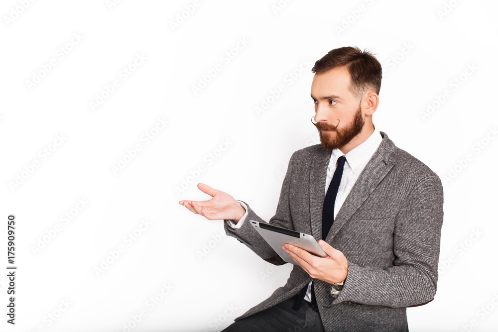 Serious man in grey suit talks something holding tablet in his arm Serious man in grey suit talks something holding tablet in his arm