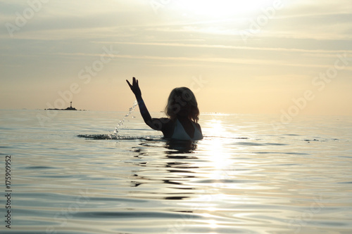 silhouette woman in the sea playing under the sunset in the peaceful island